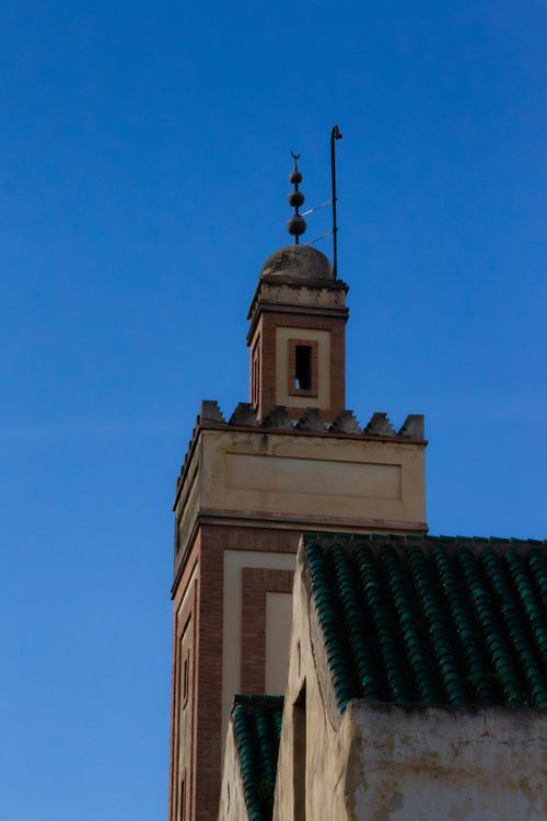 Free A traditional Moroccan minaret in Fes with intricate design under a bright blue sky. Stock Photo