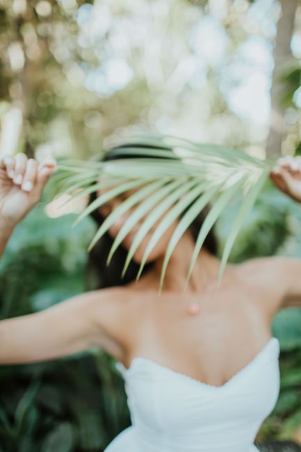 Artistic portrait of a woman holding a palm leaf, creating a tropical and mysterious ambiance.