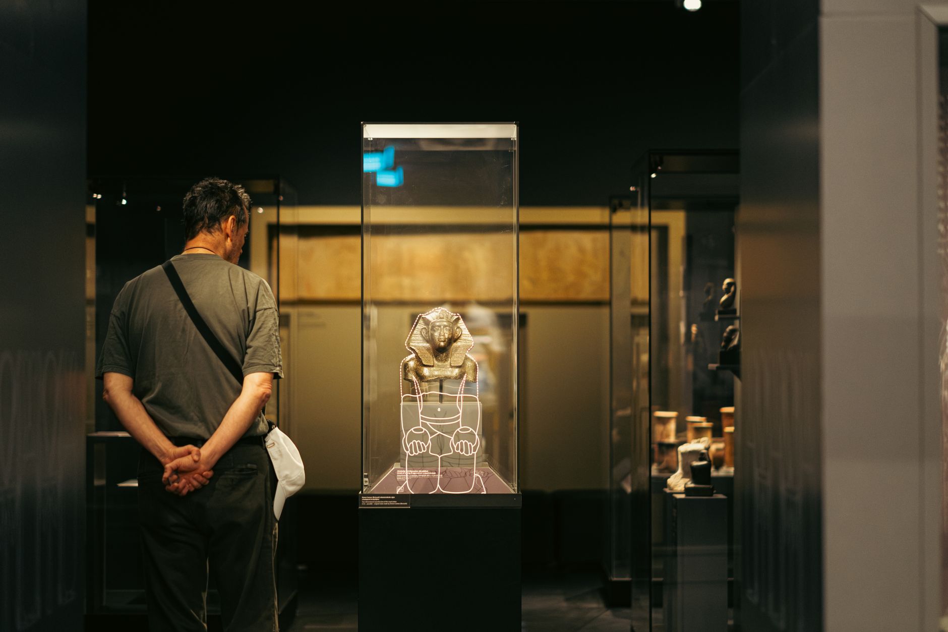 A museum curator examining ancient rooster pottery under warm gallery lighting, surrounded by historical artifacts