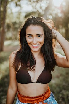 一位穿着比基尼、笑容灿烂的无忧无虑女子，正在户外享受阳光明媚的日子