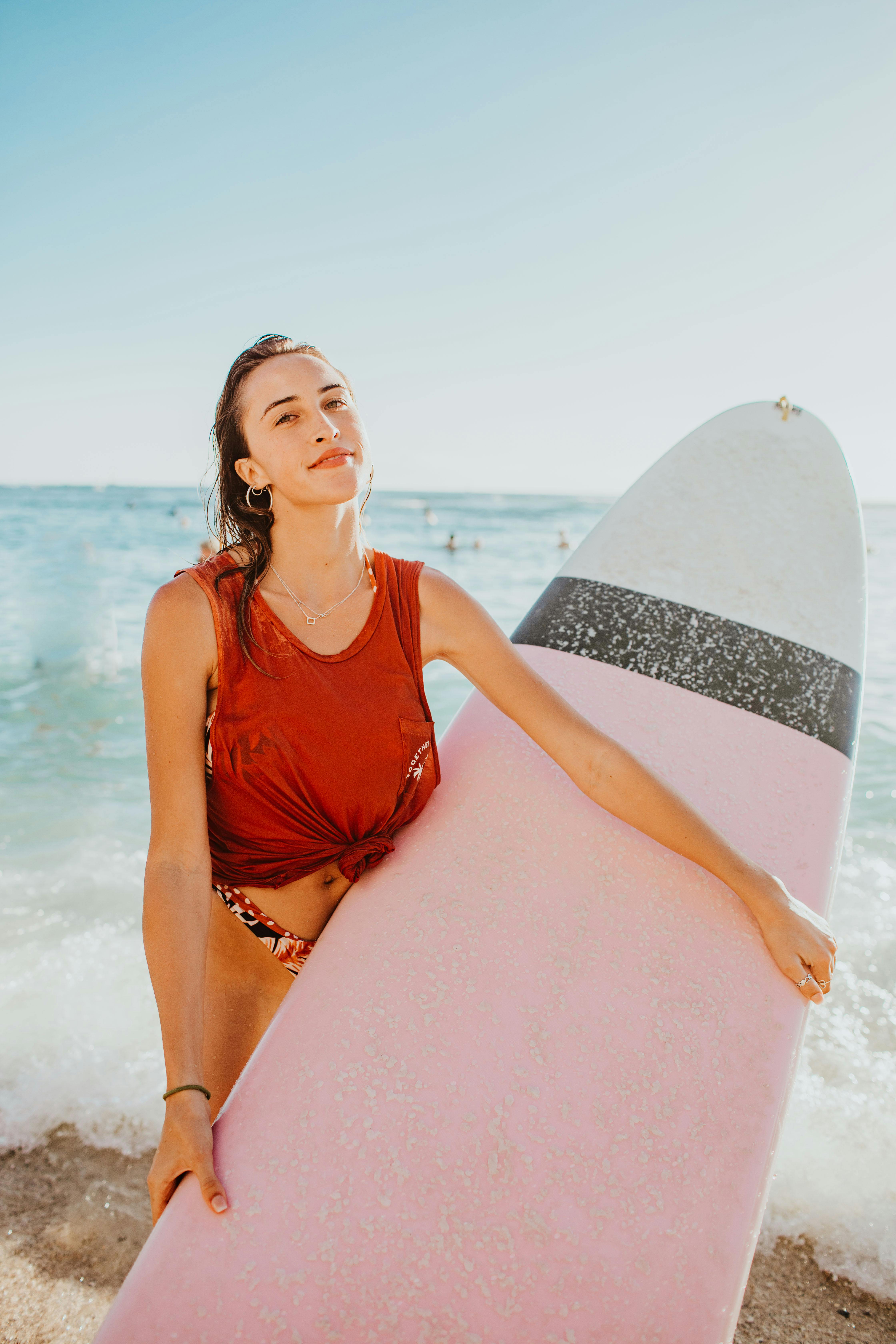 阳光明媚的夏威夷海滩上，一位自信的女人拿着粉色冲浪板，享受着热带氛围