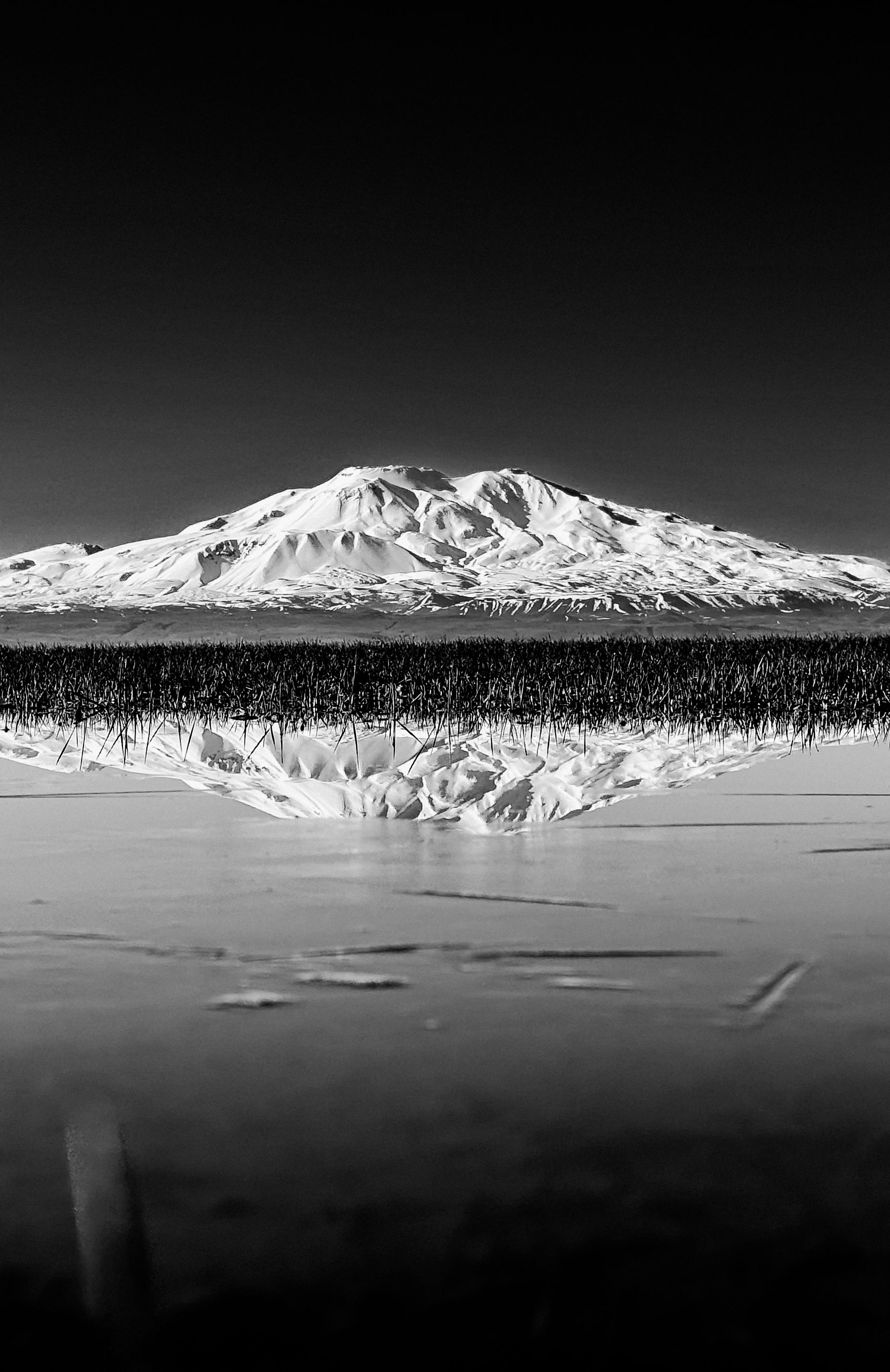 Stunning black and white photo of a mountain reflecting in the water, offering a serene natural view.