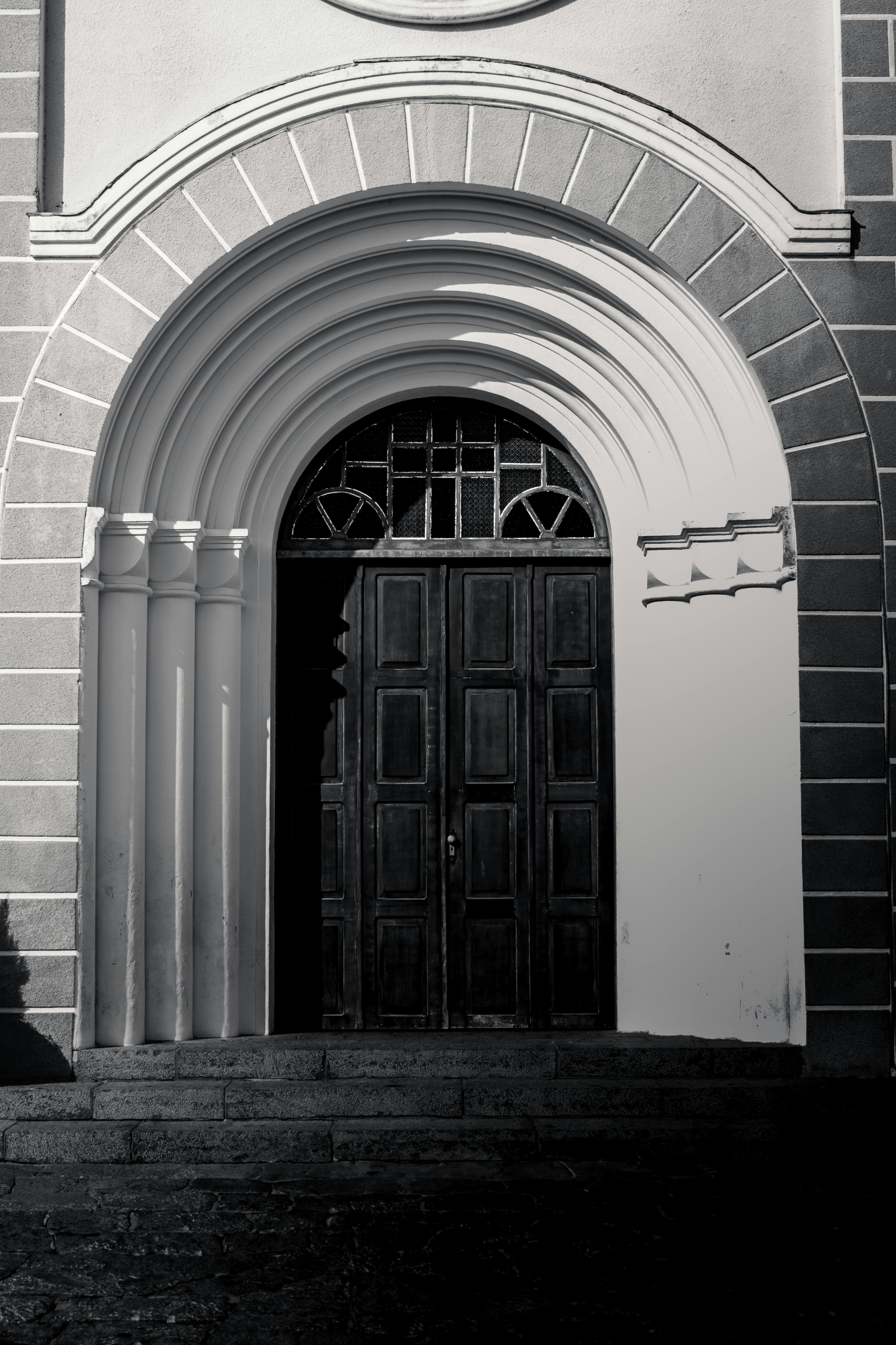 Black and white photo of a historic church entrance in Luiz Alves, showcasing architectural details.