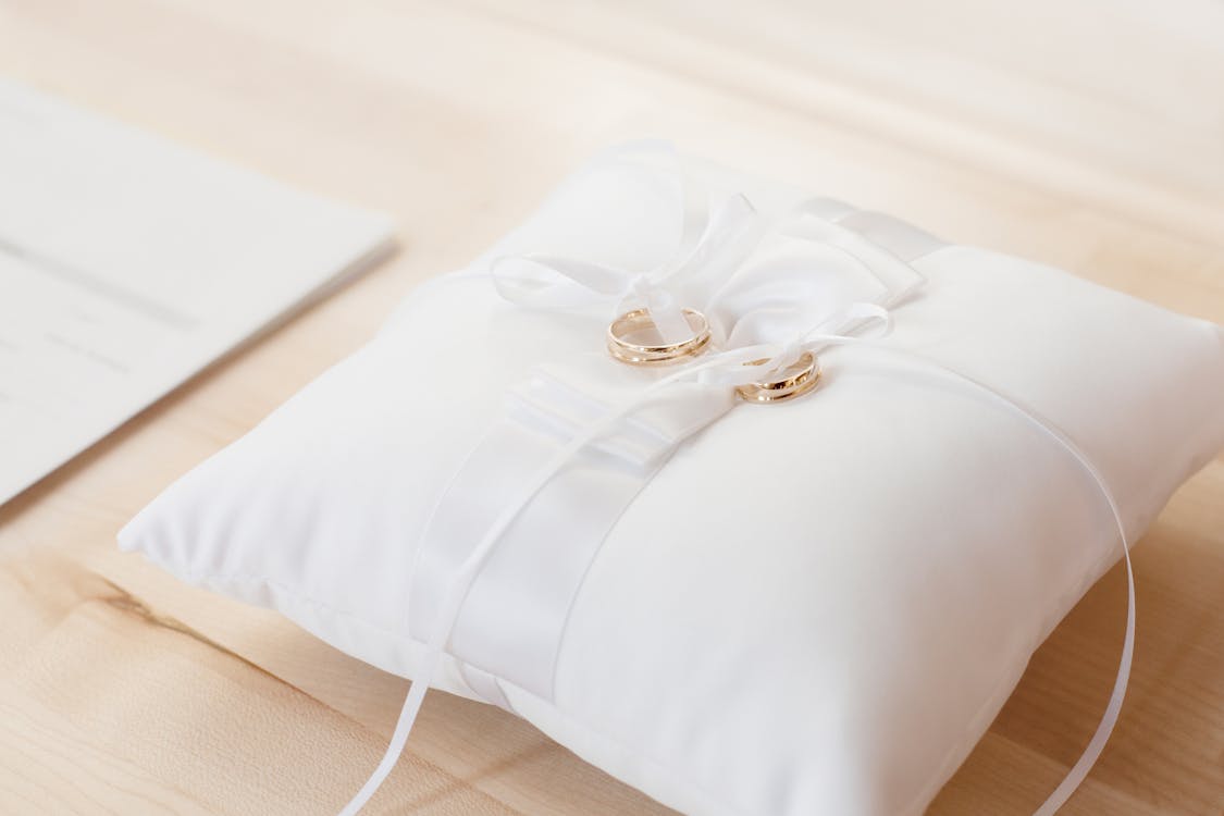 無料 白い枕の上に金のブライダルリングのペアのクローズアップ写真 写真素材