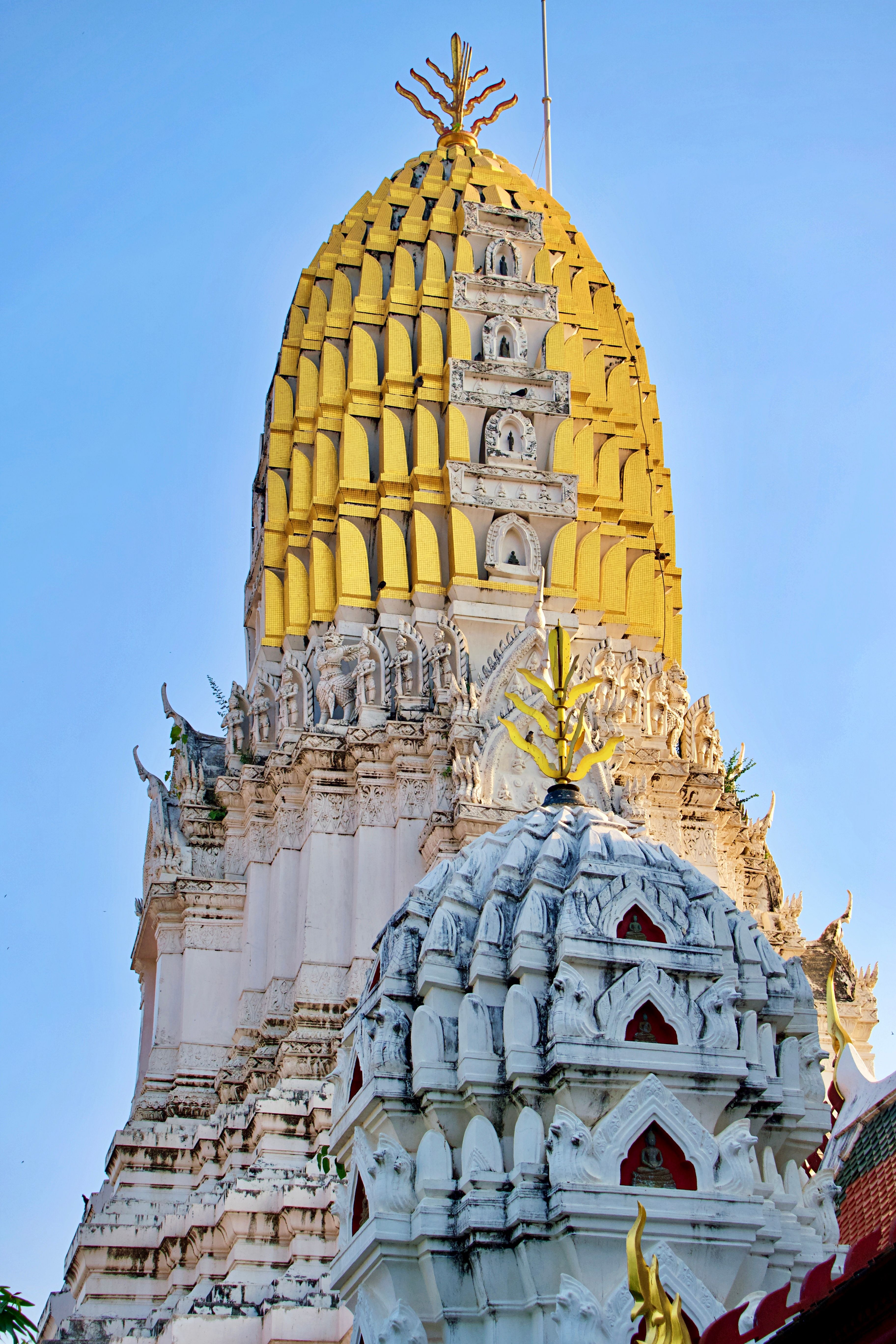 Majestic golden stupa of Wat Phra Si Ratana Mahathat under clear blue sky.