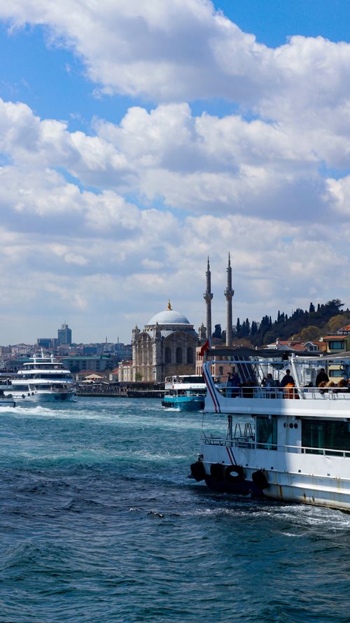 Free Bosphorus strait with boats and iconic Ortaköy Mosque in Istanbul under a bright sky. Stock Photo