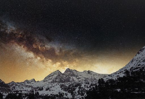 A breathtaking view of the Milky Way galaxy over snow-capped mountains, captured on a clear night.