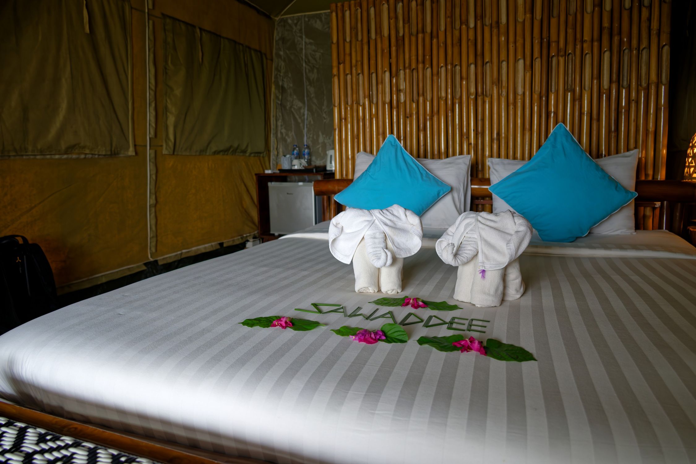 Elegant resort bedroom in Thailand featuring unique elephant towel art and decorative pillows.