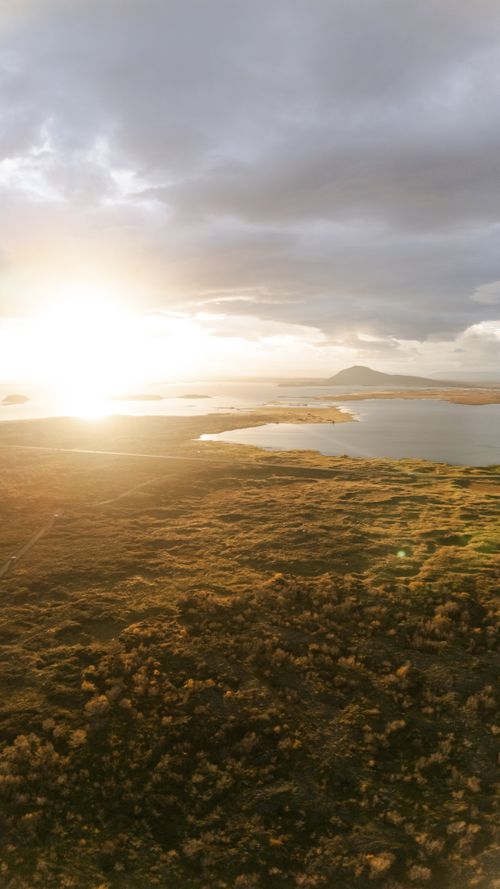 Free A breathtaking sunrise illuminates a lush island landscape with a serene lake. Stock Photo