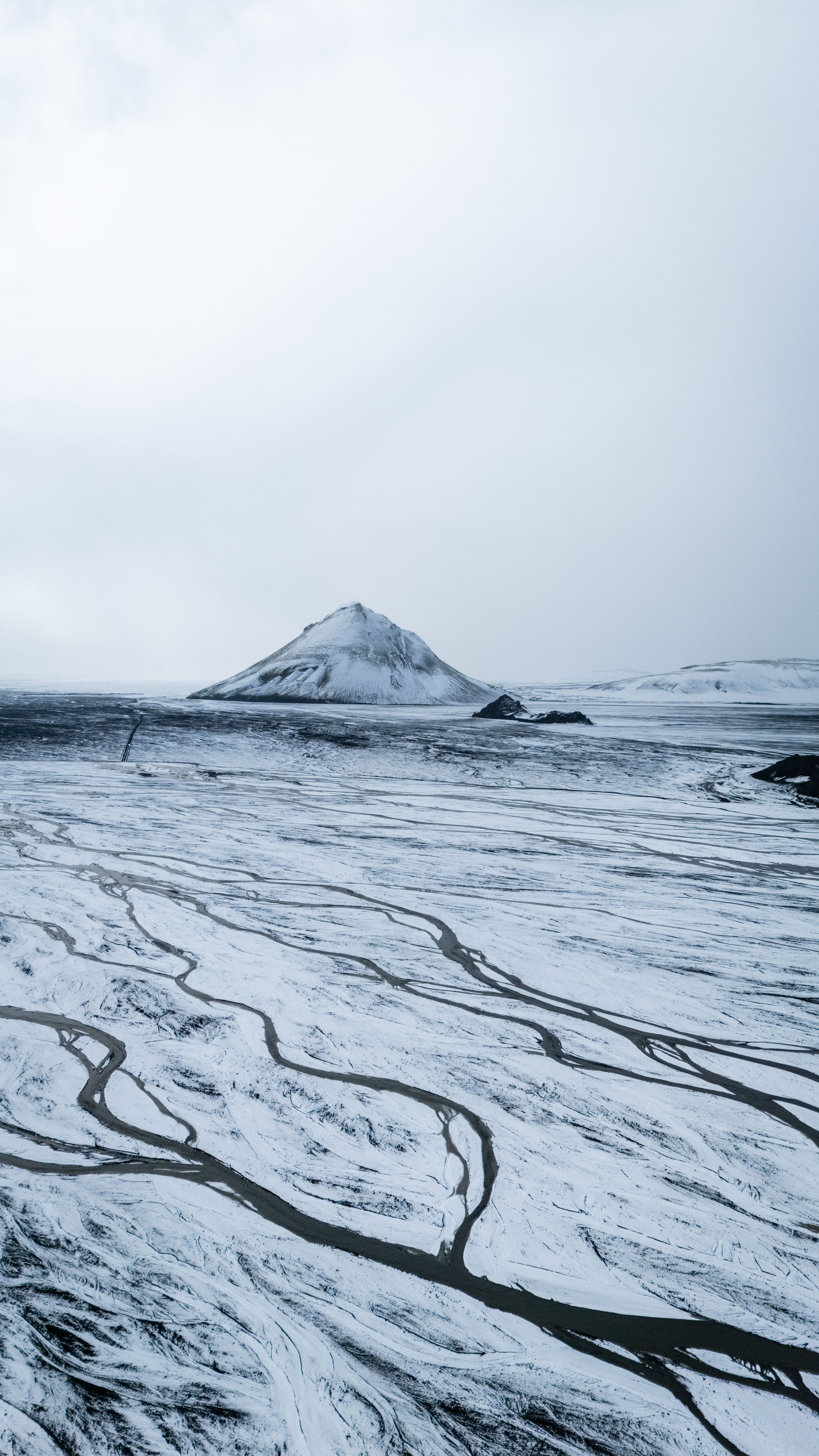 A stunning aerial shot of a snow-covered mountain on an island, showcasing winter's beauty.