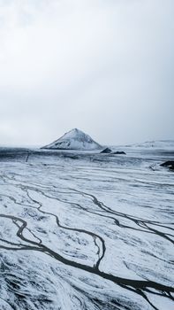 A stunning aerial shot of a snow-covered mountain on an island, showcasing winter's beauty.