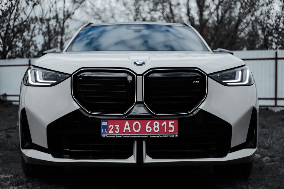 A sleek front view of a BMW car featuring a Ukrainian license plate outdoors.