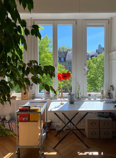 A well-lit home office with a large window overlooking a lush garden.