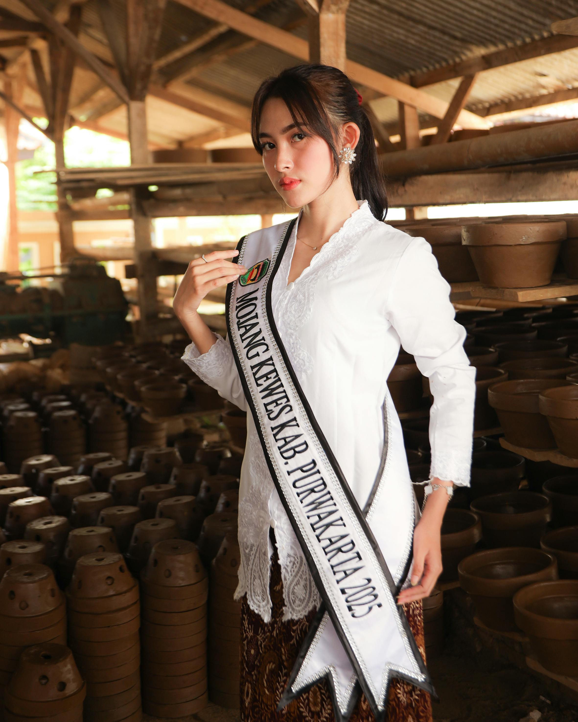 Elegant woman in traditional dress posing in a pottery workshop with sash Mojang Kewes Kab Purwakarta 2023.