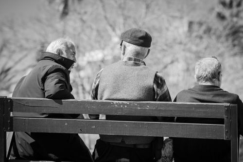 Free Three senior men enjoying a conversation on a park bench. Black and white imagery. Stock Photo