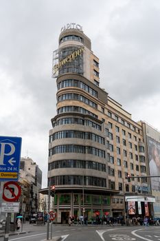 View of the famous Edificio Carrión in Madrid, showcasing its unique architecture under cloudy skies.