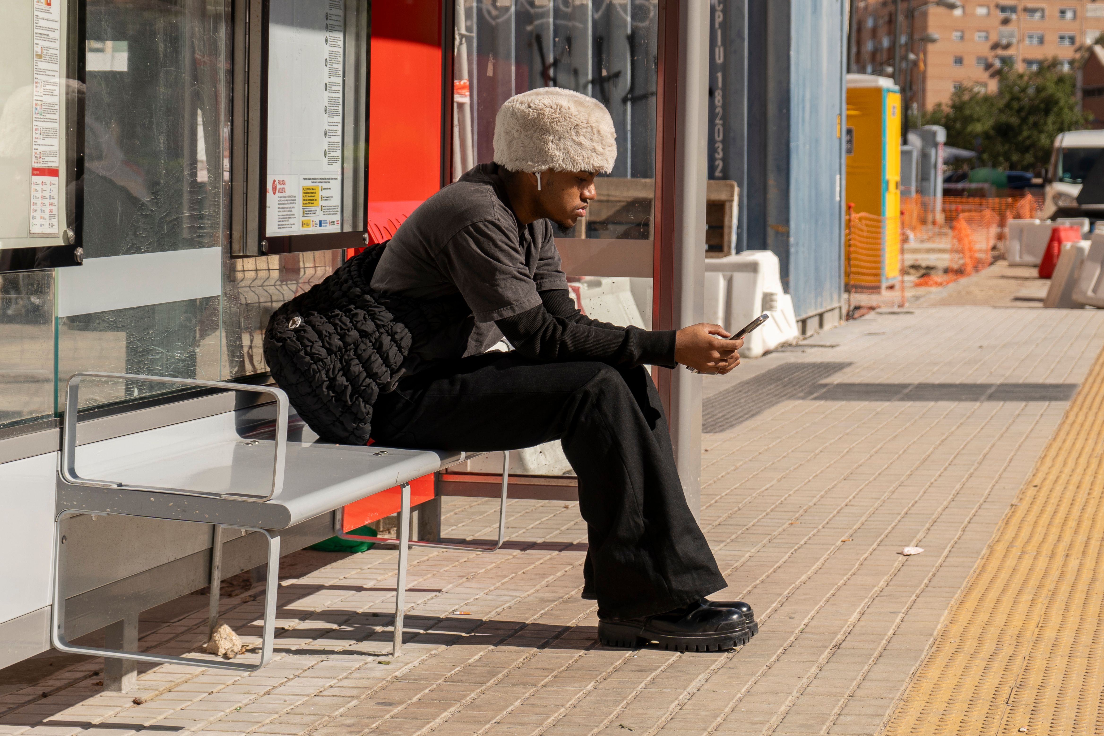 Traveller waiting at a bus stop below the Roman aqueduct in Segovia