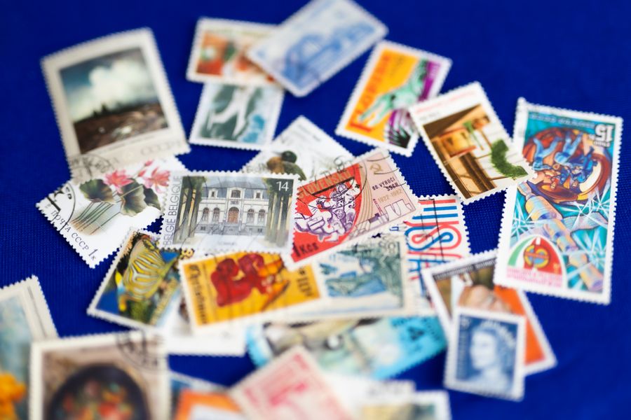 A collection of colorful vintage postage stamps scattered on a vibrant blue background.