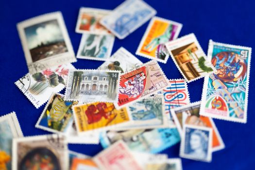 A collection of colorful vintage postage stamps scattered on a vibrant blue background.