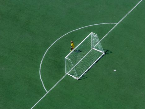 Aerial shot of a child goalkeeper in a soccer field during daytime.