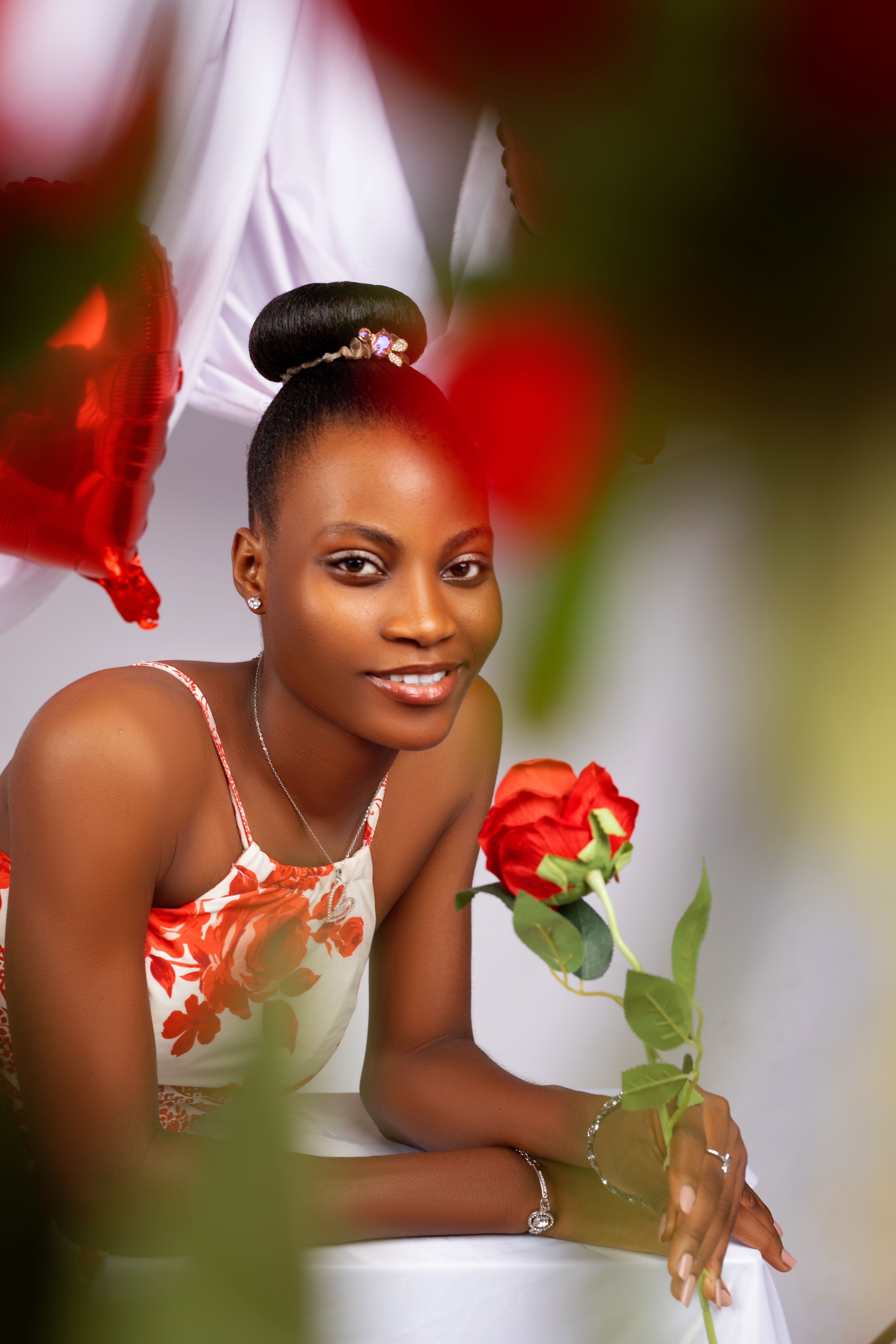 A stylish woman in floral dress with red rose, ideal for romantic themes.