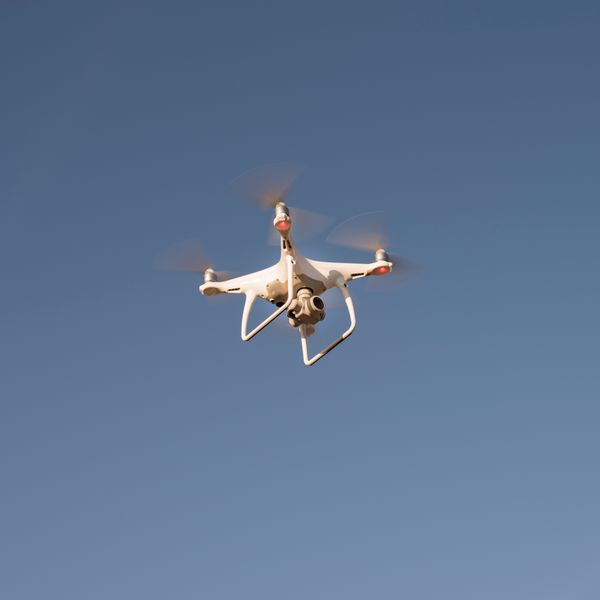 White drone flying against blue sky