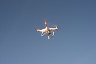 一架白色无人机在晴朗的蓝天上飞行，展现了现代技术