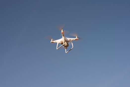 Capture of a white drone flying against a clear blue sky, showcasing modern technology.