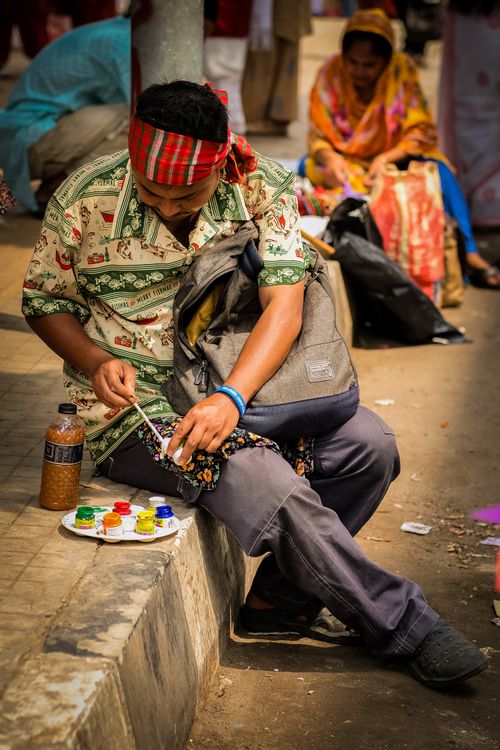 Free A street artist painting on the sidewalk surrounded by passersby. Creative urban scene. Stock Photo