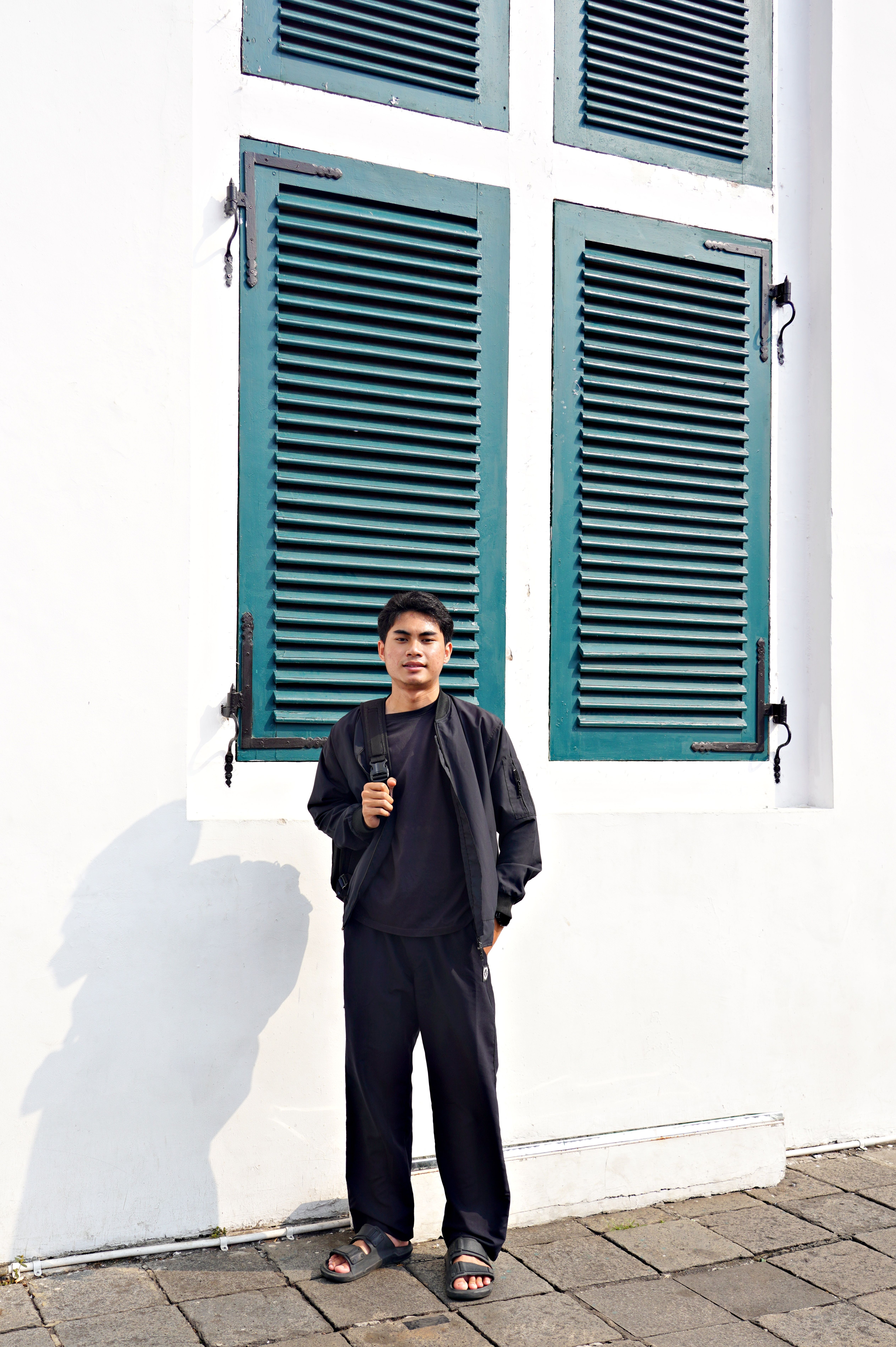 Young man standing by vintage window shutters · Free Stock Photo