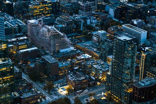 Aerial view of Toronto's urban skyline at twilight, featuring tall buildings and city lights.