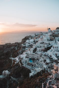 当太阳落在海边标志性的白色建筑上时，您可以在希腊圣托里尼岛欣赏壮丽景色，放松身心