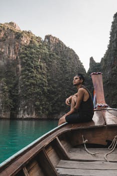 在泰国甲米，一名男子乘船游览，四周石灰岩悬崖环绕，海水清澈，宁静宜人