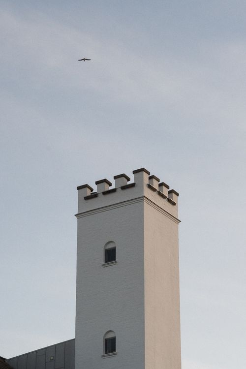 Free Minimalist view of a historic tower in Norway with a bird flying in the clear sky. Stock Photo