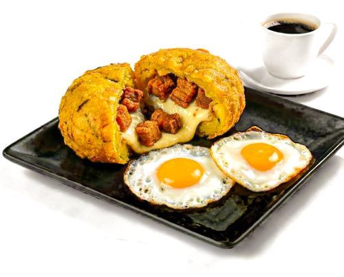Delicious Ecuadorian breakfast featuring mote pillo, fried eggs, and coffee on a black plate.