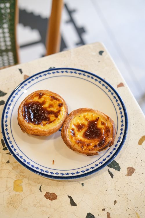 Free Close-up of two traditional Pastel de Nata pastries served on a decorative plate. Stock Photo