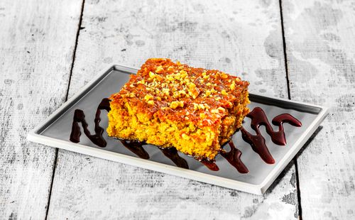 Free A close-up of a corn cake with nuts and chocolate sauce, served on a rustic wooden table. Stock Photo