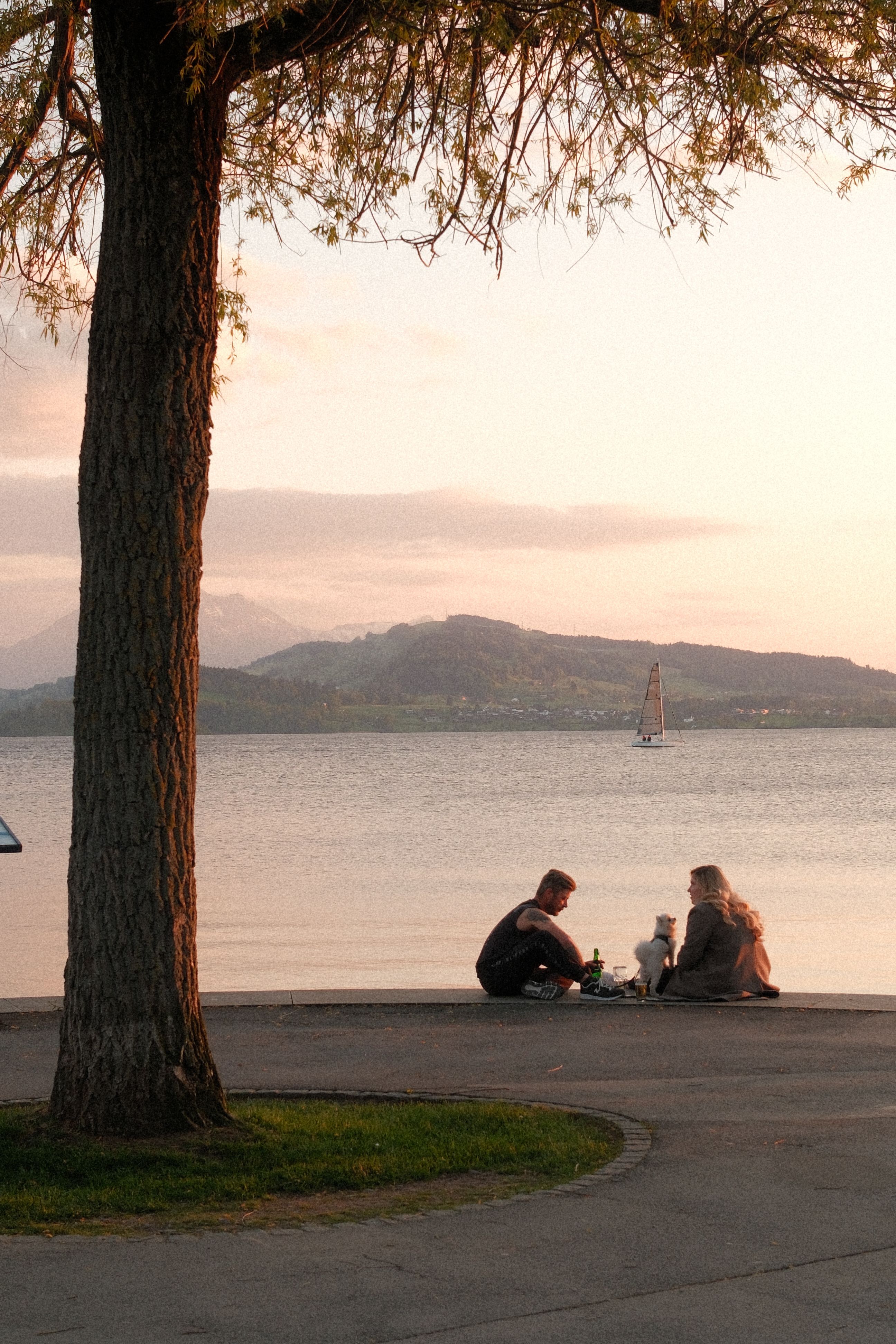 Couple enjoying a peaceful sunset picnic by Lake Zug, Switzerland with scenic mountains.