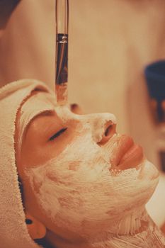 Adult woman receiving a soothing facial mask application at a modern spa.