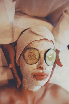 A calming spa scene with facial treatment, using cucumber slices and face mask.