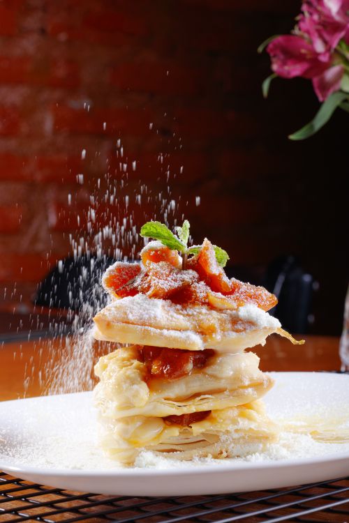 Free Delicious stacked pastry dessert with a dusting of powdered sugar and mint garnish, perfect for gourmet dining. Stock Photo