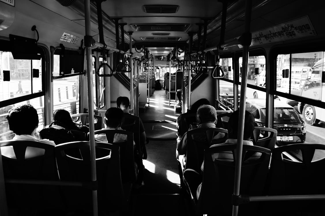 Foto En Escala De Grises De Personas Sentadas Dentro De Un Autobús