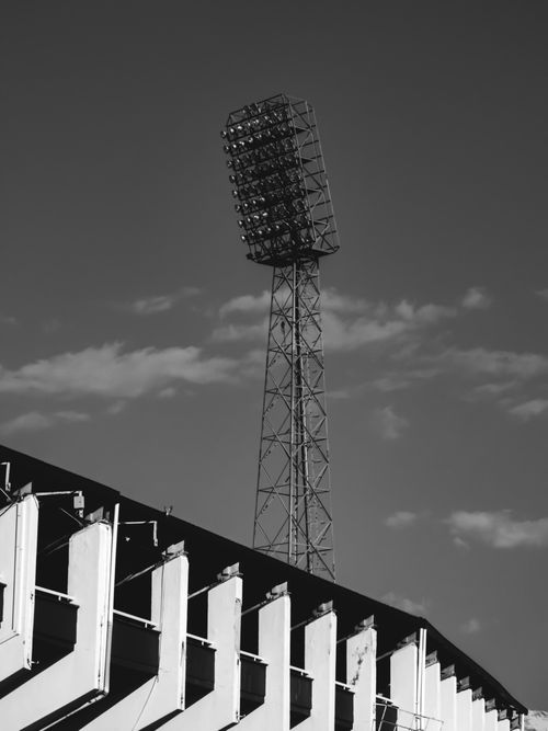 Free Dramatic black and white photo of a stadium floodlight against a clouded sky. Stock Photo