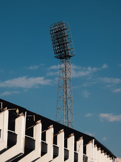 Free A tall stadium floodlight tower set against a bright blue clear sky. Stock Photo