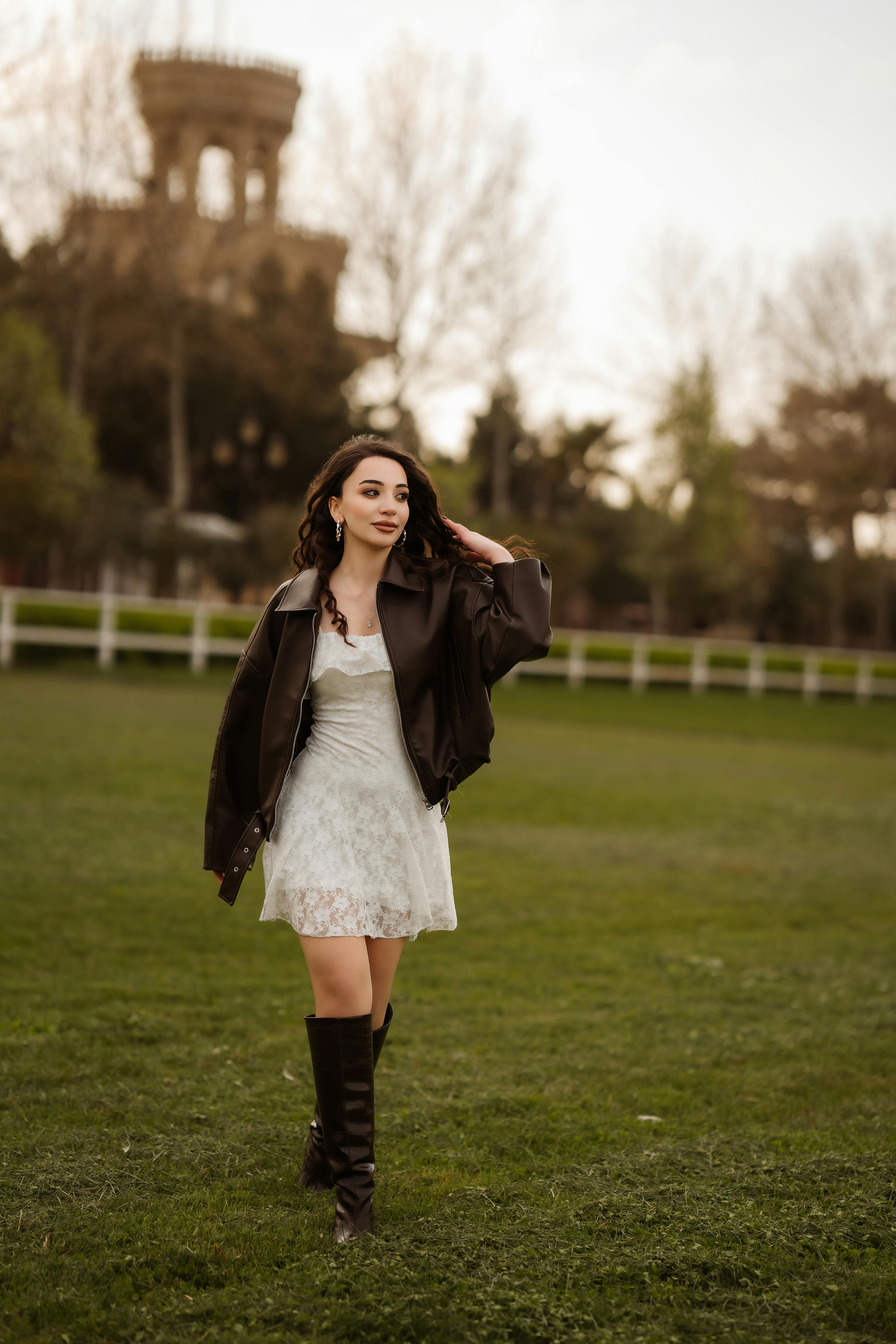 A stylish young woman walks through a lush park in Baku, dressed in fashionable attire.