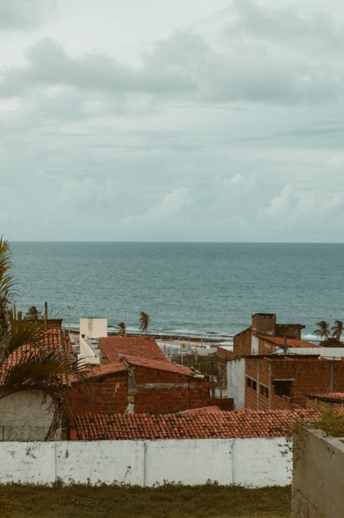 Free Scenic view of Natal, Brazil, featuring red rooftops and ocean under a cloudy sky. Stock Photo