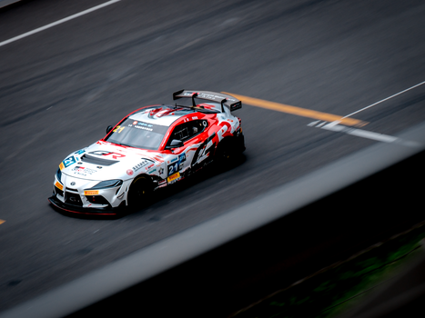 Dynamic shot of a racing car speeding on an asphalt track during a race.