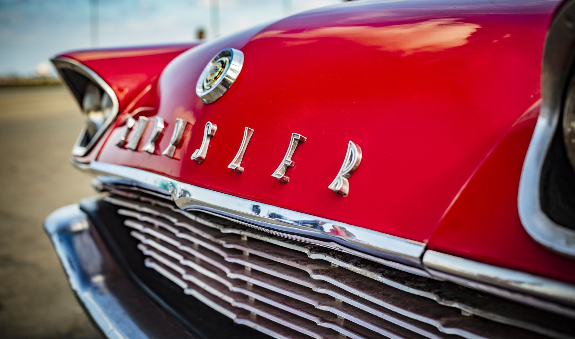 Detailed close-up of a classic red Chrysler car grille with chrome lettering.