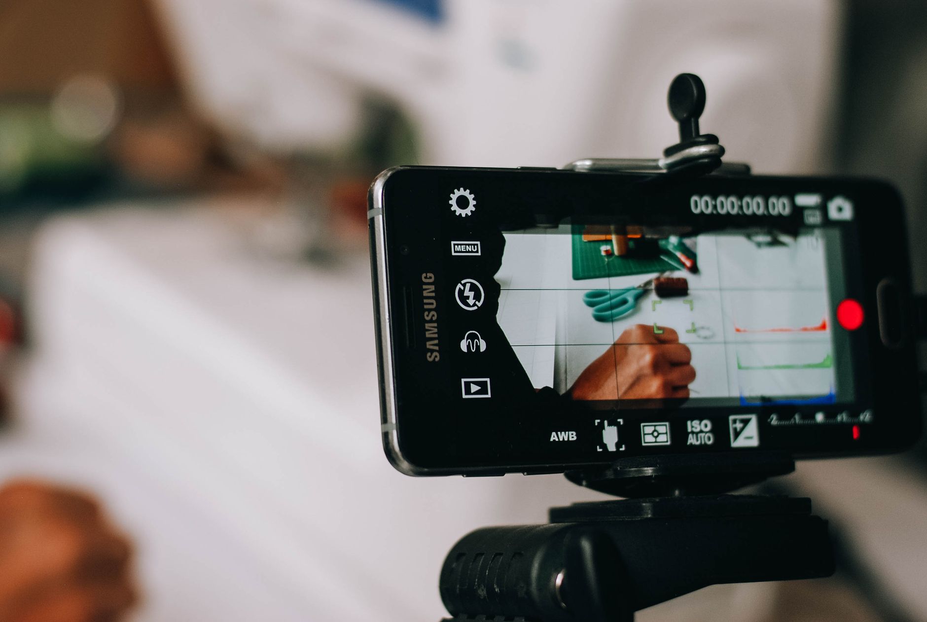Smartphone on tripod capturing person writing on paper, showing content creation process.