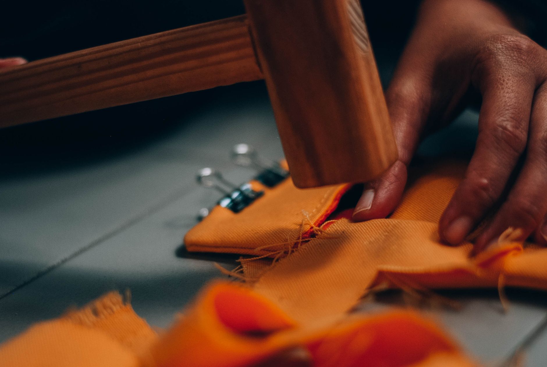 Hands sewing upholstery by hand, underscoring the tactile labour behind furniture that resists screen-flat interiors.